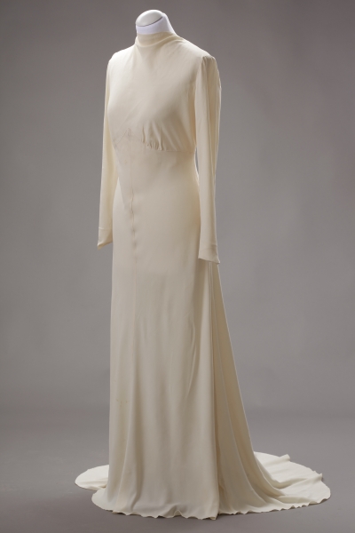 Šaty svatební smetanové barvy z hedvábné tkaniny v keprové vazbě, 1938. Šaty přiléhavé linie mají oblíbený zvýšený pas a ve spodní části se postupně rozšiřují v okrouhlou vlečku. Šaty patřily Marii Fischerové, která si v nich vzala 4. 7. 1938 JUDr. Václava Hrnčíře. Spolu se svatební čelenkou, dvěma věnečky a proutěnými košíčky pro družičky je věnovala do sbírek Národního muzeu v roce 2009 paní Marie Michálková, dcera Marie Hrnčířové. 