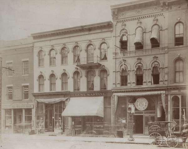 Fotografie zachycující druhé působiště Vojty Náprstka v Milwaukee. V popisce pod fotografií je uvedeno: „Tyto domy stojí na západní straně tak řečeného tržiště na němž byla nyní postavena naše radnice... Ta tři okna pod balkonem byla do jeho místností, malými dvířky po straně se vcházelo. Dům jest nyní poněkud vyzdoben, patro s balkonem jest nové, krám Gustava Martiniho jest značně změněn ale přes to vše jest to stále dosud týž dům...“ Zdroj: Národní muzeum Fotografie. Fotografie zachycující druhé působiště Vojty Náprstka v Milwaukee. V popisce pod fotografií je uvedeno: „Tyto domy stojí na západní straně tak řečeného tržiště na němž byla nyní postavena naše radnice... Ta tři okna pod balkonem byla do jeho místností, malými dvířky po straně se vcházelo. Dům jest nyní poněkud vyzdoben, patro s balkonem jest nové, krám Gustava Martiniho jest značně změněn ale přes to vše jest to stále dosud týž dům...“