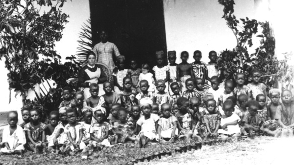 Děti z Basilejské misie s misionářkou a místní vychovatelkou před vchodem do školy. Ghana (Zlaté pobřeží), 1885-1888. Zdroj: Národní muzeum Fotografie. Děti z Basilejské misie s misionářkou a místní vychovatelkou před vchodem do školy. Ghana (Zlaté pobřeží), 1885-1888. Zdroj: Národní muzeum