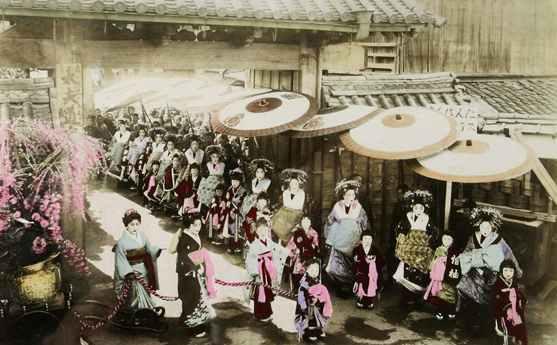Průvod kurtizán (jap. Oiran dóčú), neznámý fotograf, černobílá, ručně kolorovaná fotografie. Zakoupeno patrně v roce 1906, sbírka Joe Hlouchy. Zdroj: Národní muzeum Kolorovaná fotografie Průvod kurtizán