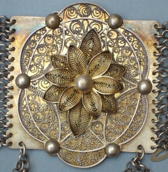 Filigránové rozety ze stříbrného pásu. Na sponě je puncovní značka „E. W.“ – Emil Wotke, zlatník krojových šperků působící přímo v Těšíně – 1885–1924. Český Těšín, Slezsko, začátek 20. století. Etnografické oddělení Národního muzea, H4-69801. Zdroj: Monika Tauberová 2012