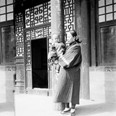 Žena s dítětem v náručí stojící na verandě domu - chůva s nejmladším dítětem mandžuského šlechtice, Vrázova přítele. Čína, Peking, 1901